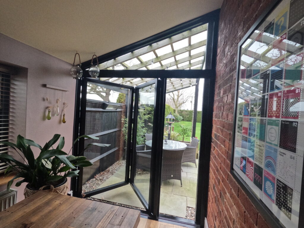 Modern conservatory with open bifold doors to garden.