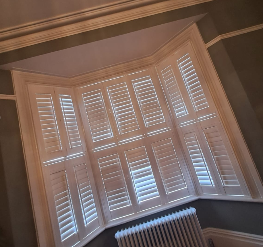 White plantation shutters fitted in a classic bay window.